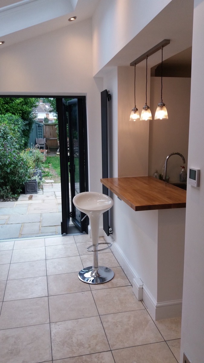 Open plan kitchen with oak breakfast bar and bifold doors