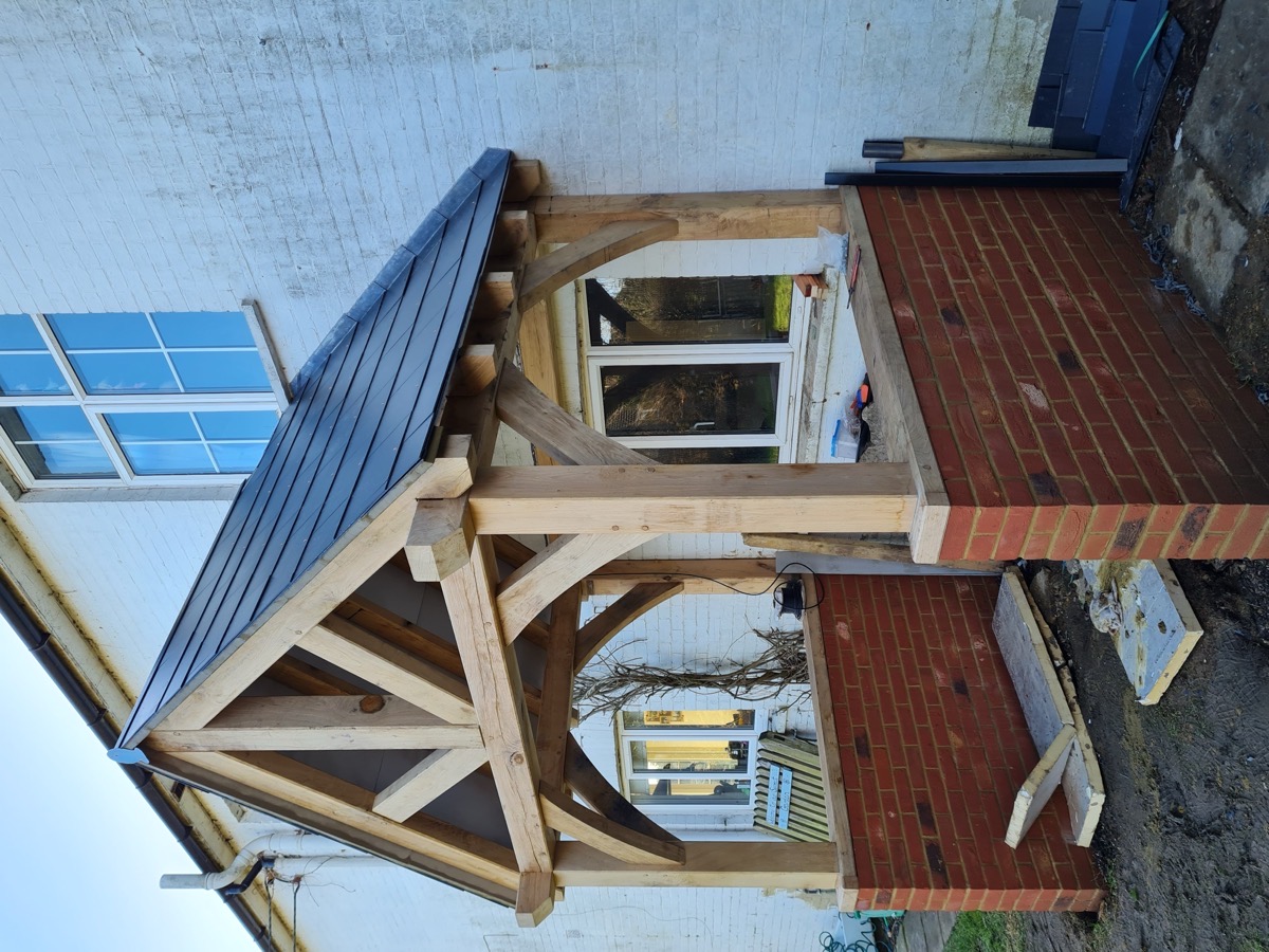 Oak framed front porch with slate tiles and brick base